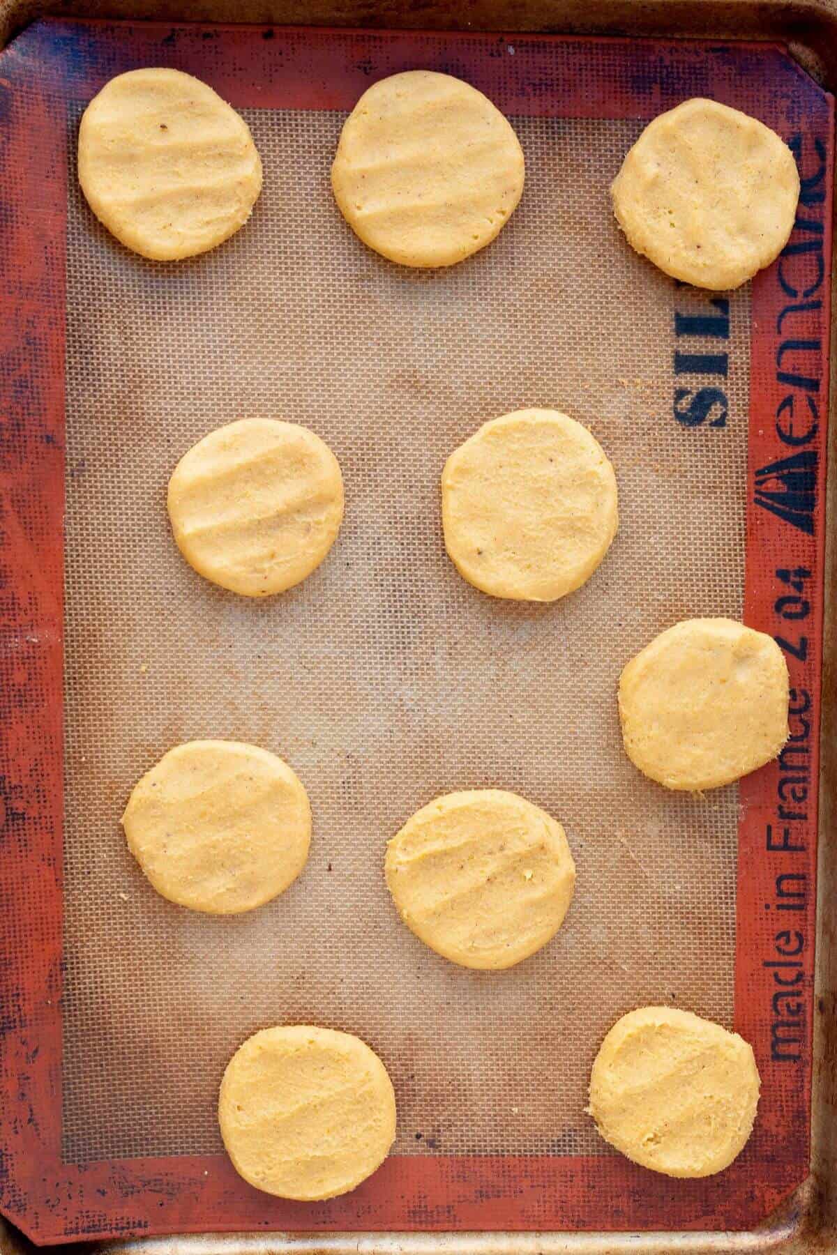 Gluten-free pumpkin cookie dough scooped and flattened on a baking tray before going into the oven.