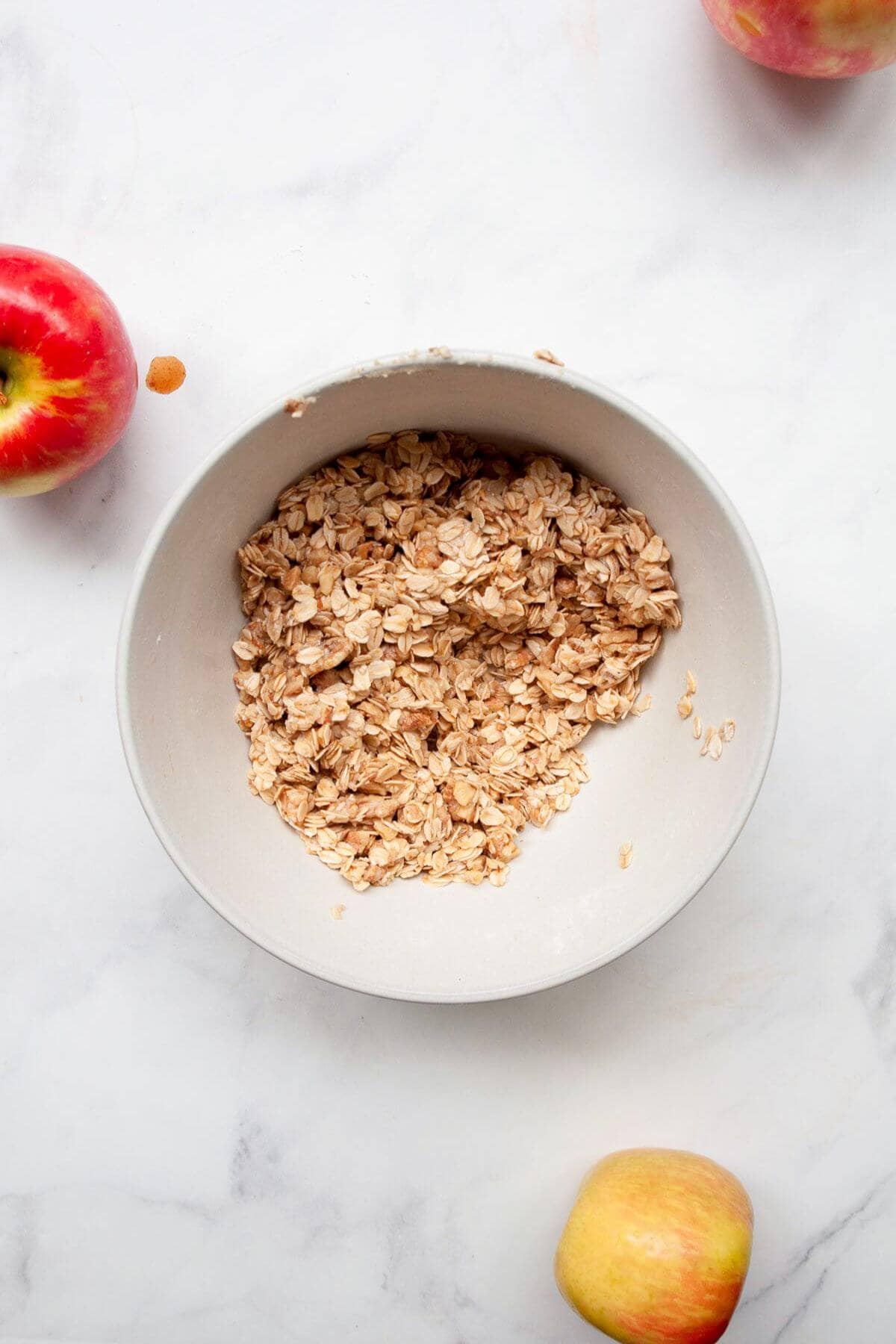 Oatmeal walnut crumble topping mixture in a mixing bowl for healthy apple crisp.