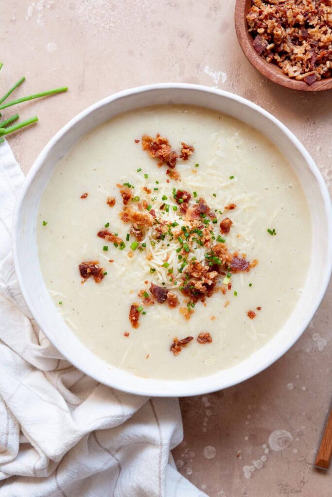 cauliflower leek potato soup with bacon crumbles, chives, and cheese on top