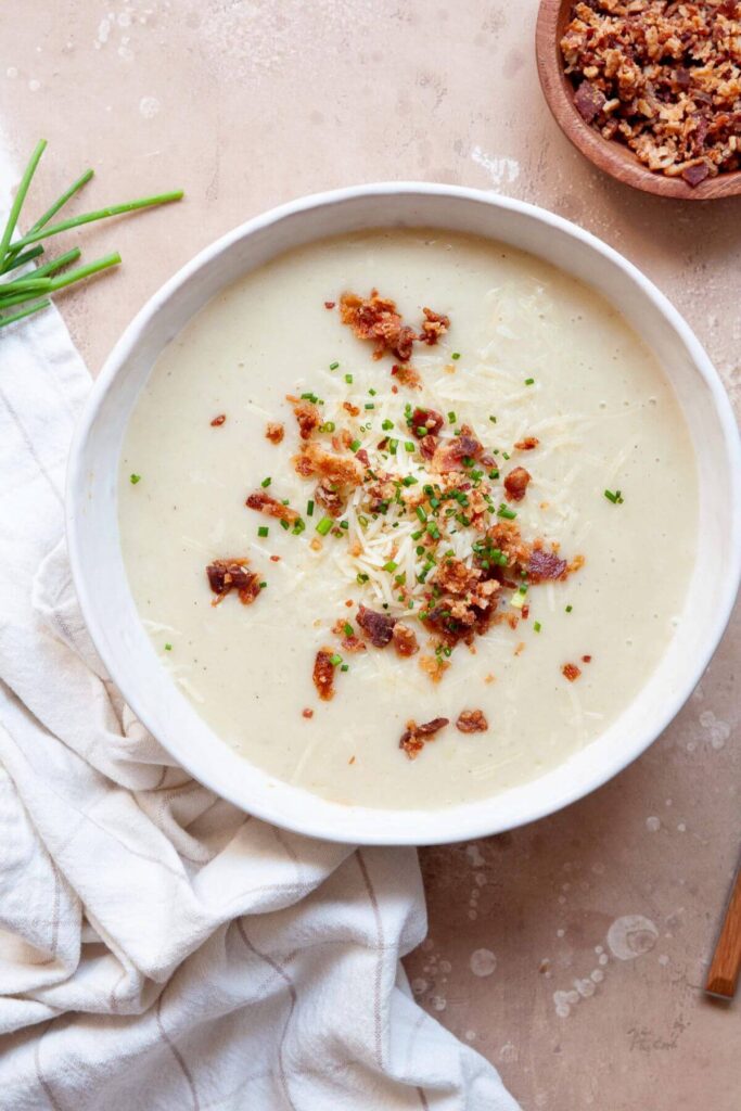 healthy creamy cauliflower leek potato soup with cheddar cheese and turkey bacon on top
