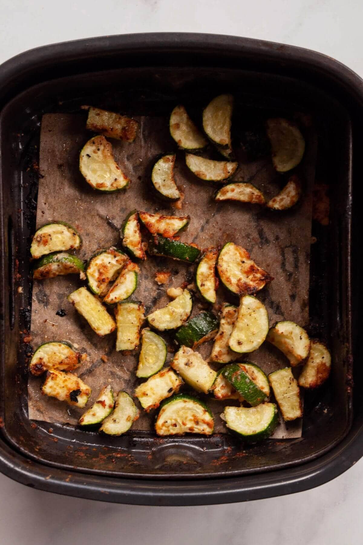 Crispy, cheesy air-fried zucchini bites with golden Parmesan edges after cooking.