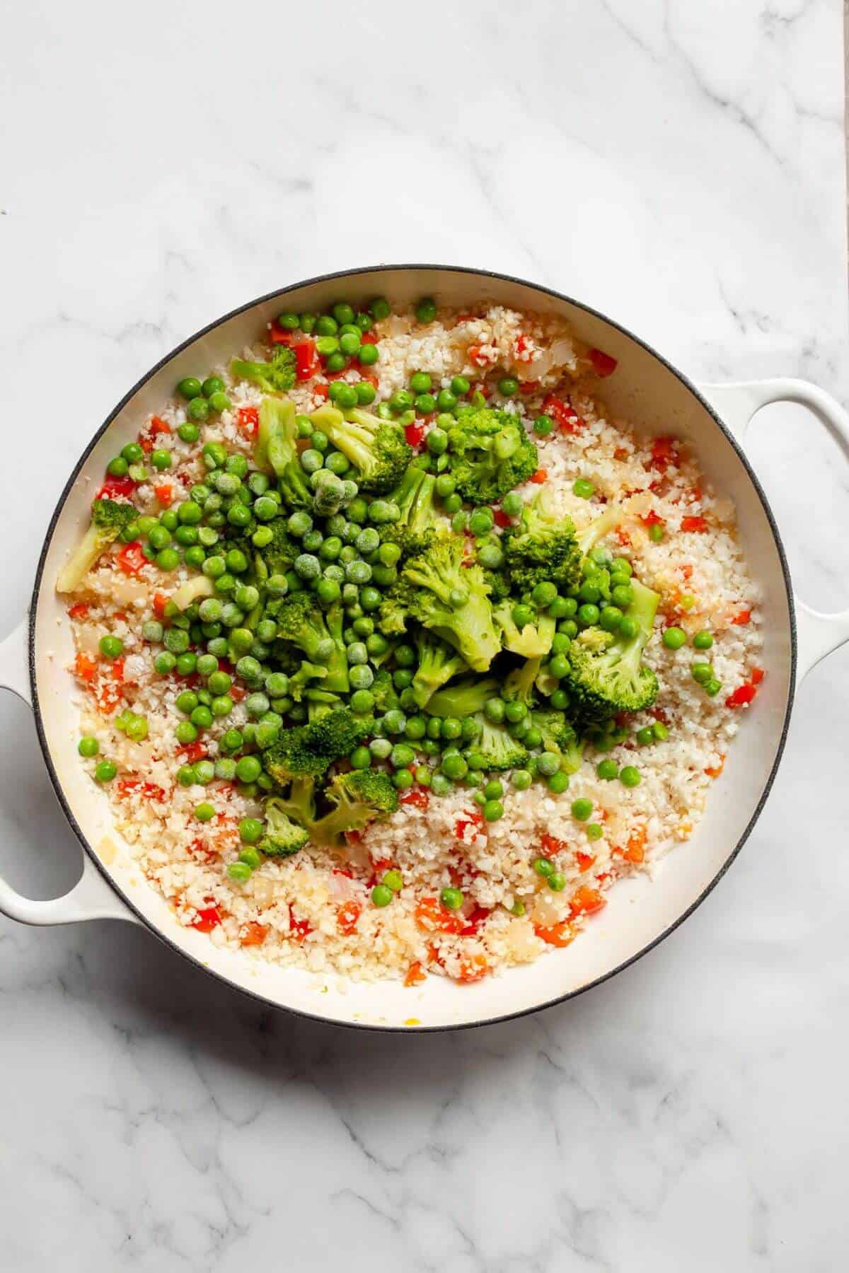 Frozen broccoli, peas, cauliflower rice, and brown rice added to the pan for healthy fried rice.