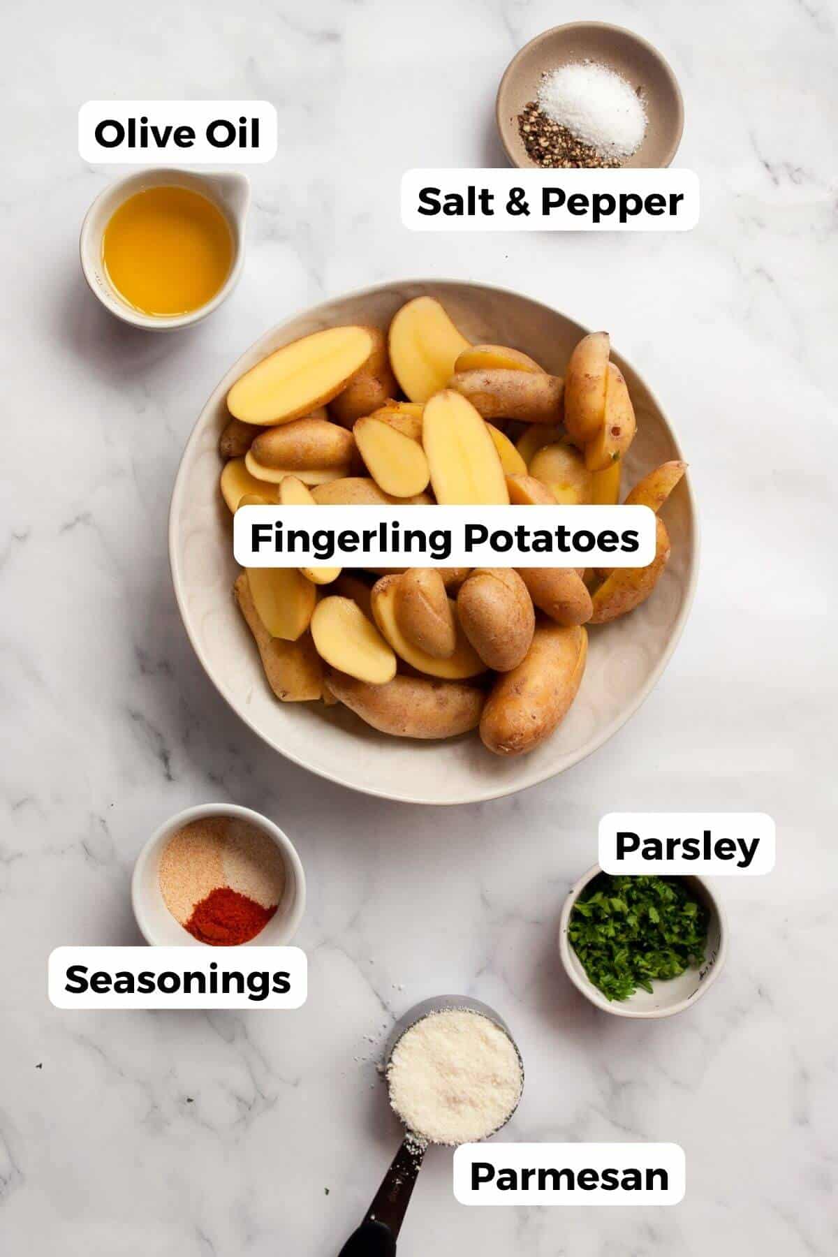 All ingredients measured out in small bowls for air fryer fingerling potatoes: halved fingerling potatoes, olive oil, grated parmesan cheese, garlic powder, onion powder, salt, pepper, and chopped parsley.