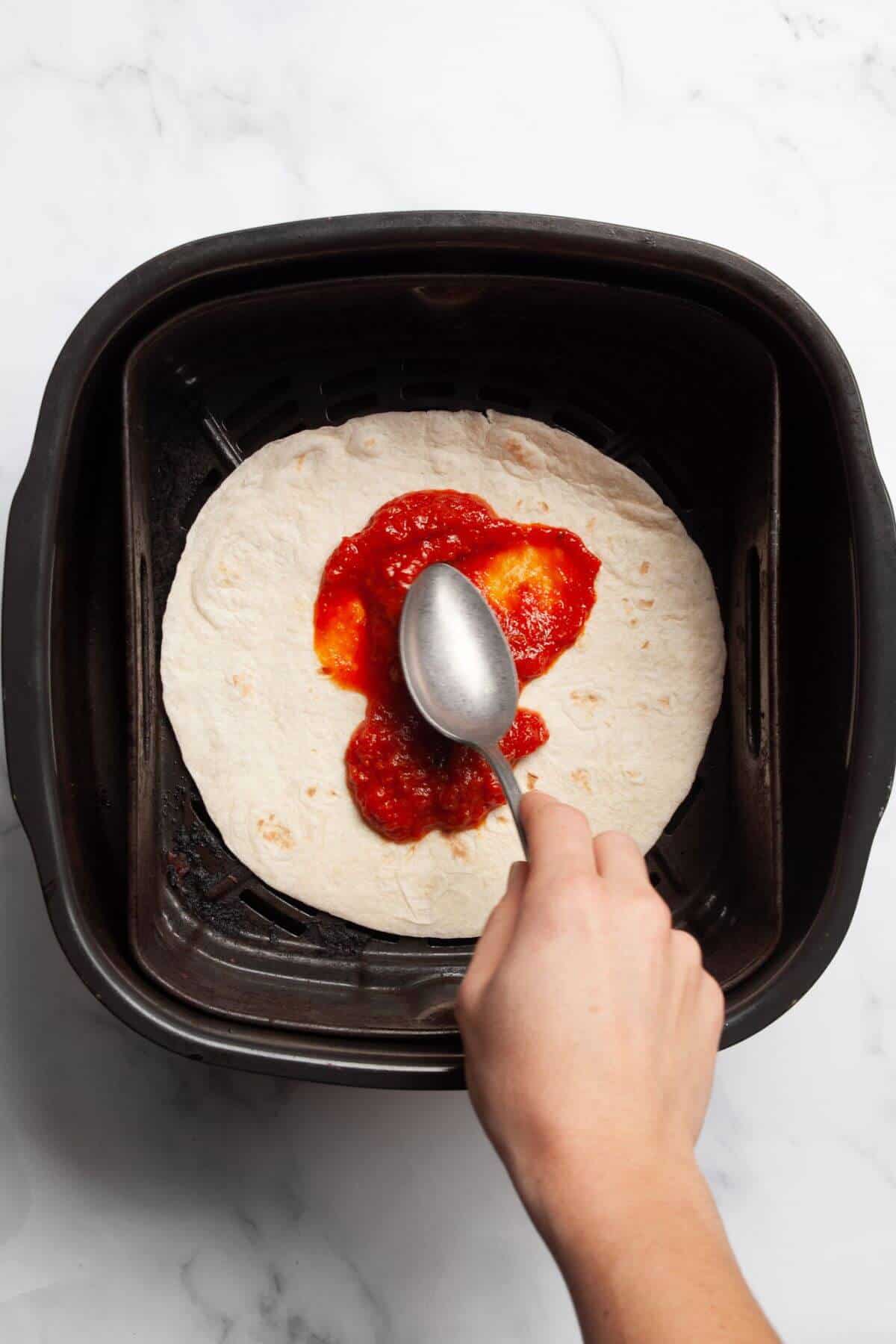 Tortilla placed in air fryer basket before adding toppings.
