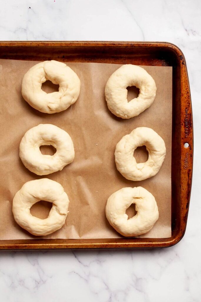 six shaped bagels on a baking sheet before adding to water bath