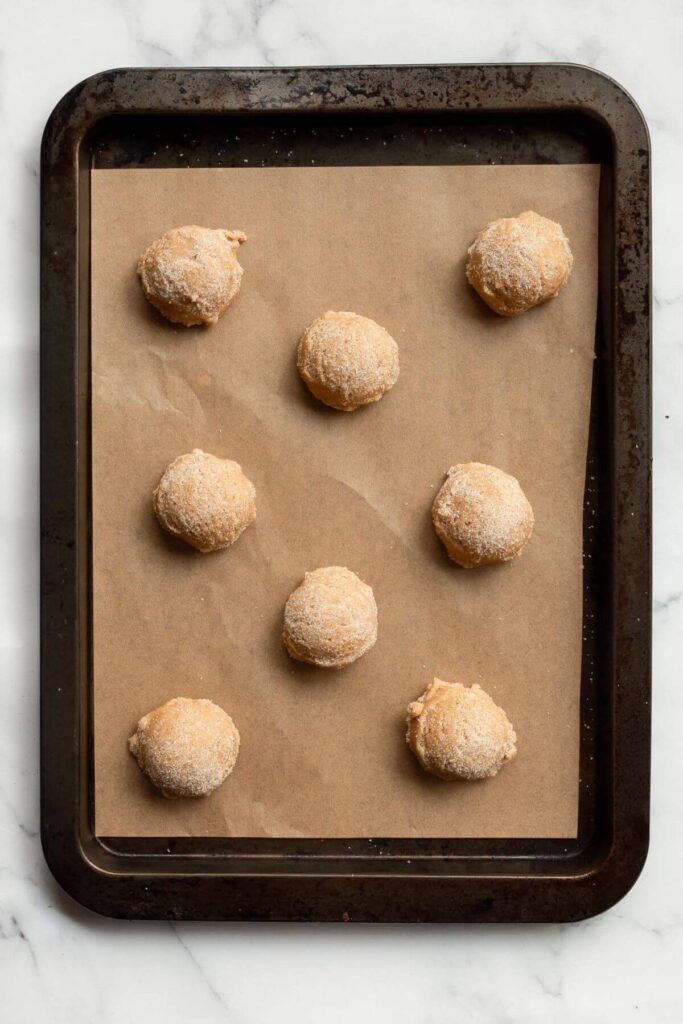 cookie dough balls rolled in sugar on baking sheet before baking