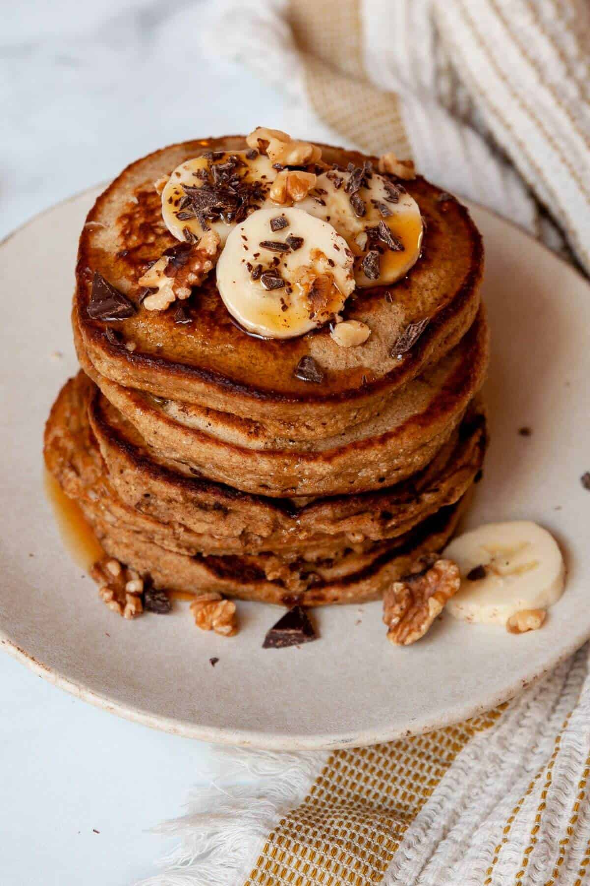Stack of chunky monkey banana pancakes with chocolate chips and walnuts on top