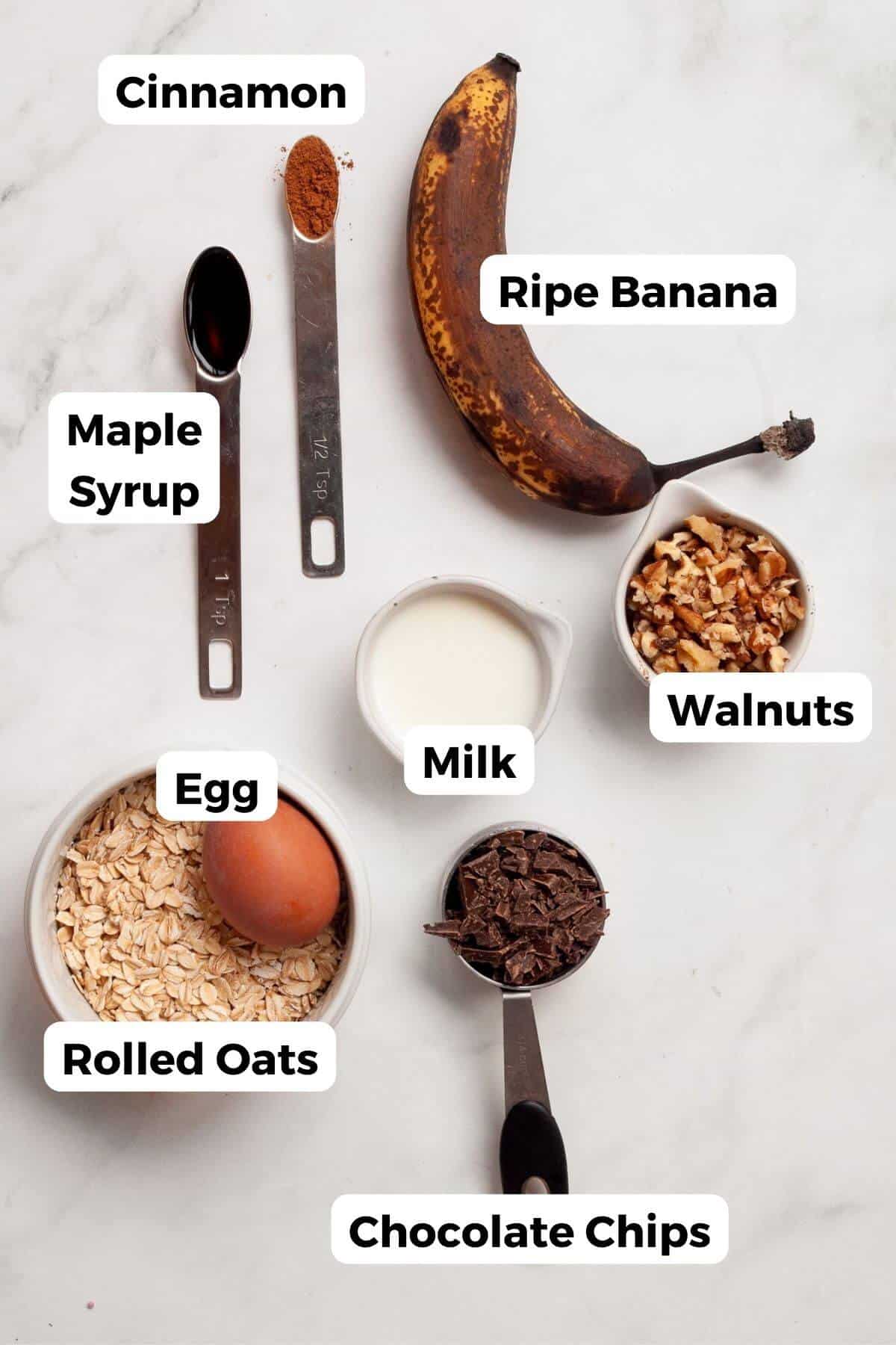 all ingredient in the pancakes including rolled oats, egg, milk, walnuts, chocolate chips, banana, maple syrup, and cinnamon