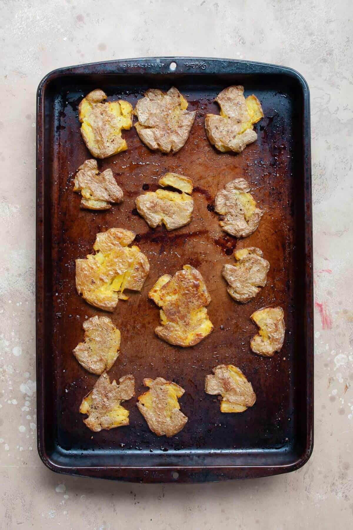 crispy smashed fingerling potatoes on a baking sheet after roasting in the oven