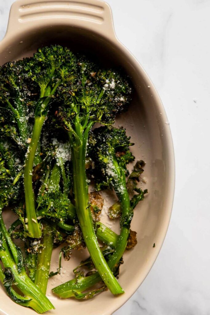 air fryer broccolini in a serving bowl with parmesan cheese and lemon