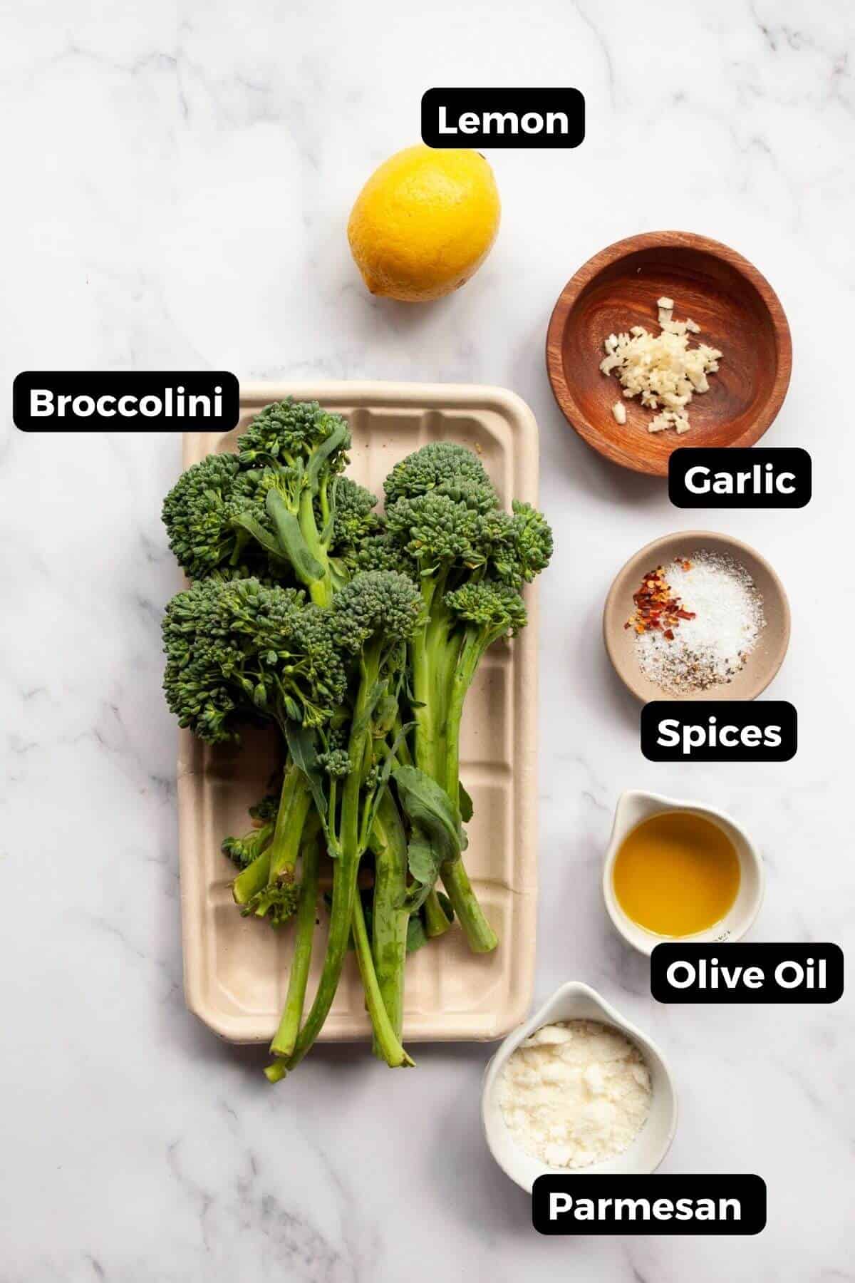 Ingredients for air fryer broccolini: broccolini, lemon, minced garlic, spices, olive oil, and parmesan.