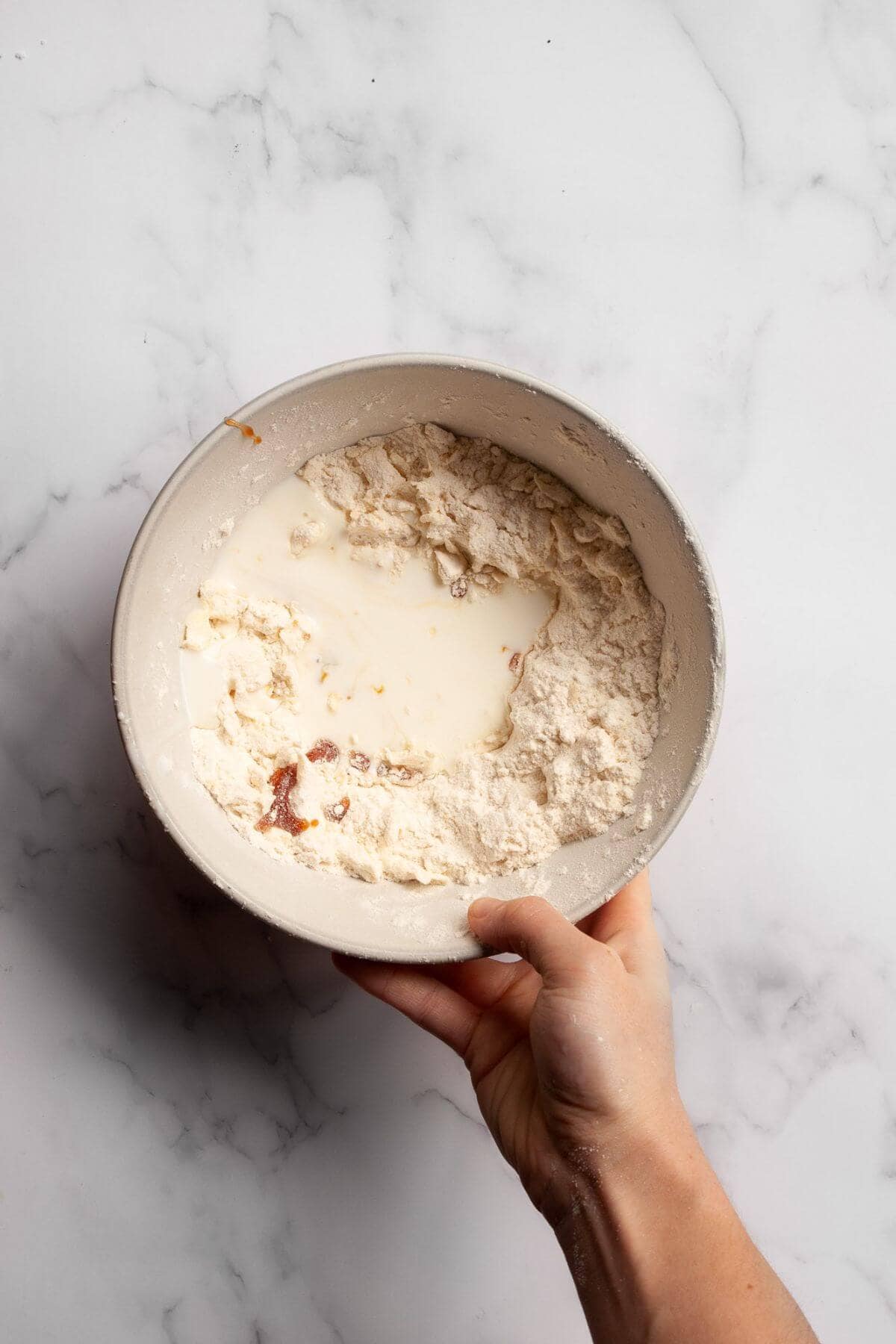 Mixing buttermilk and honey into buttered flour in a mixing bowl.