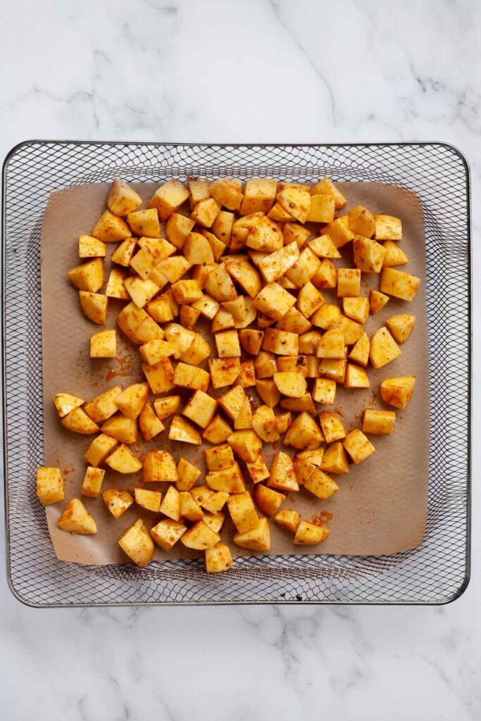 uncooked seasoned Yukon potato cubes in air fryer basket