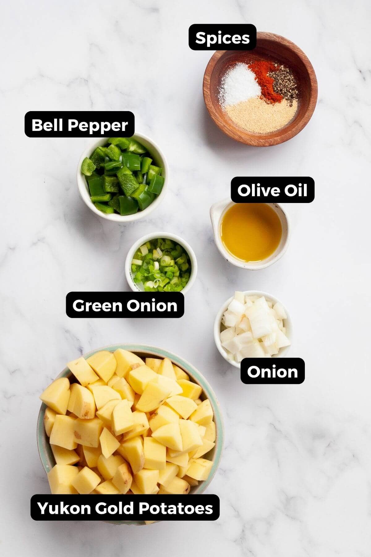 All ingredients in air fryer home fries recipe labeled, including: Yukon gold potatoes, olive oil, green onion, onion, bell pepper, and seasonings.