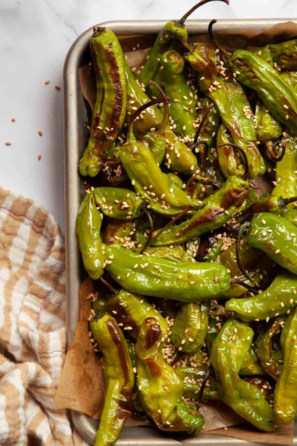 Adding sesame seeds and sesame oil to air fryer shishito peppers.