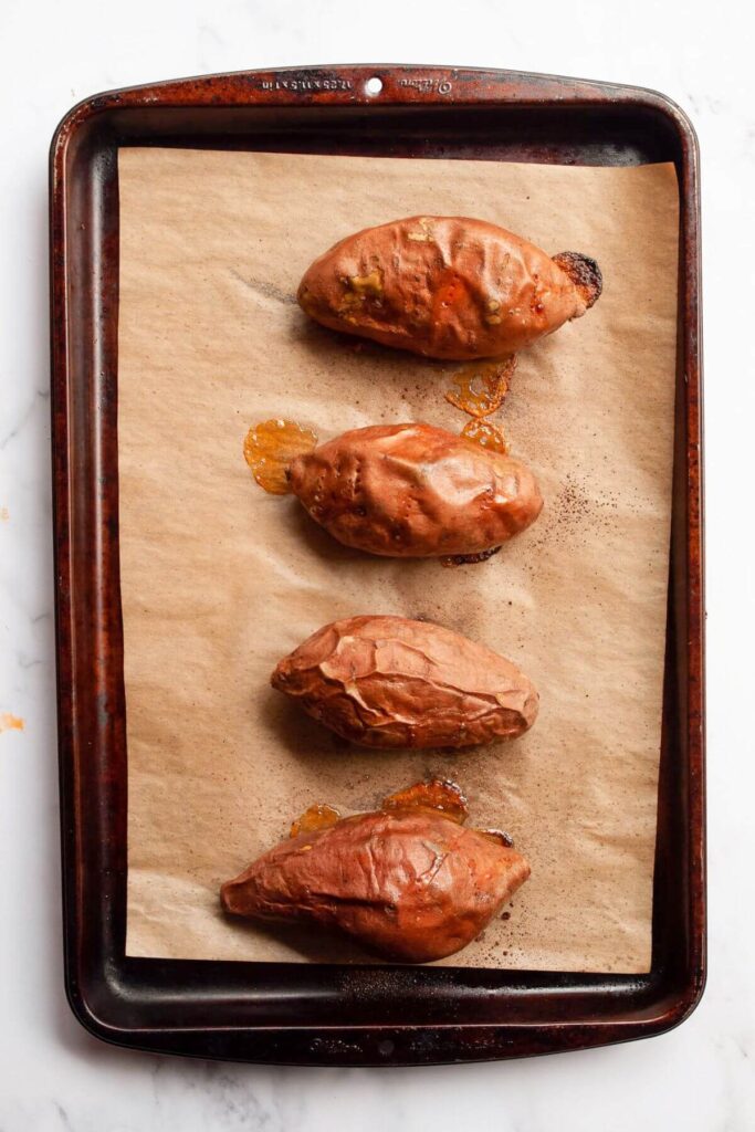 four oven roasted sweet potatoes on a baking sheet
