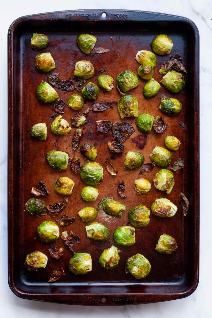 Brussels sprouts on baking sheet half way though the baking time