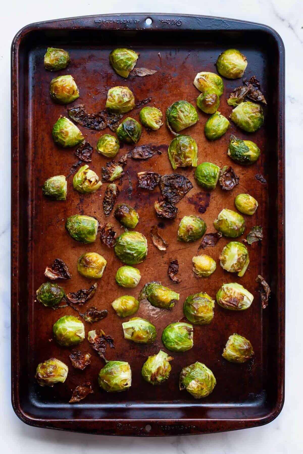 Brussels sprouts on baking sheet half way though the baking time.