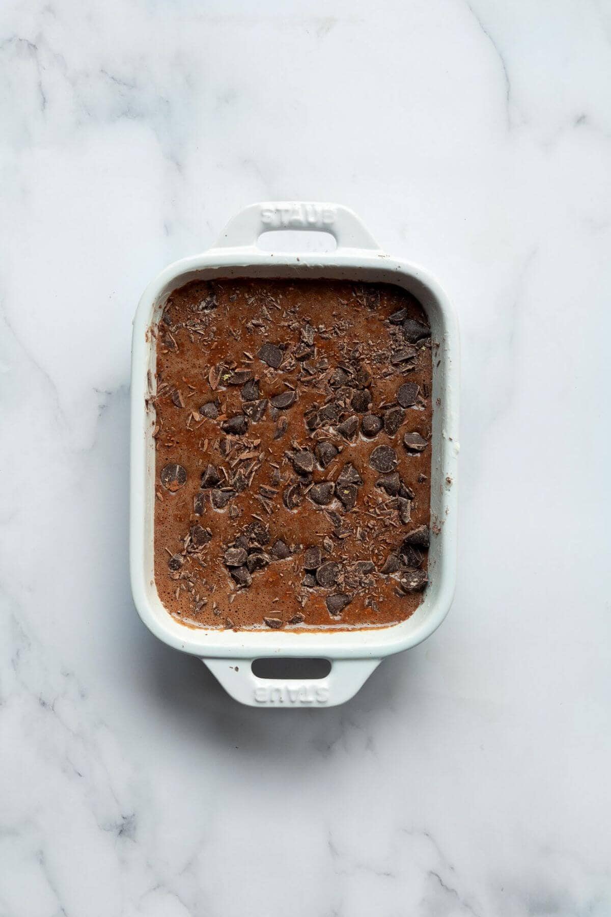 Double chocolate chip baked oats batter in a greased ramekin before baking.