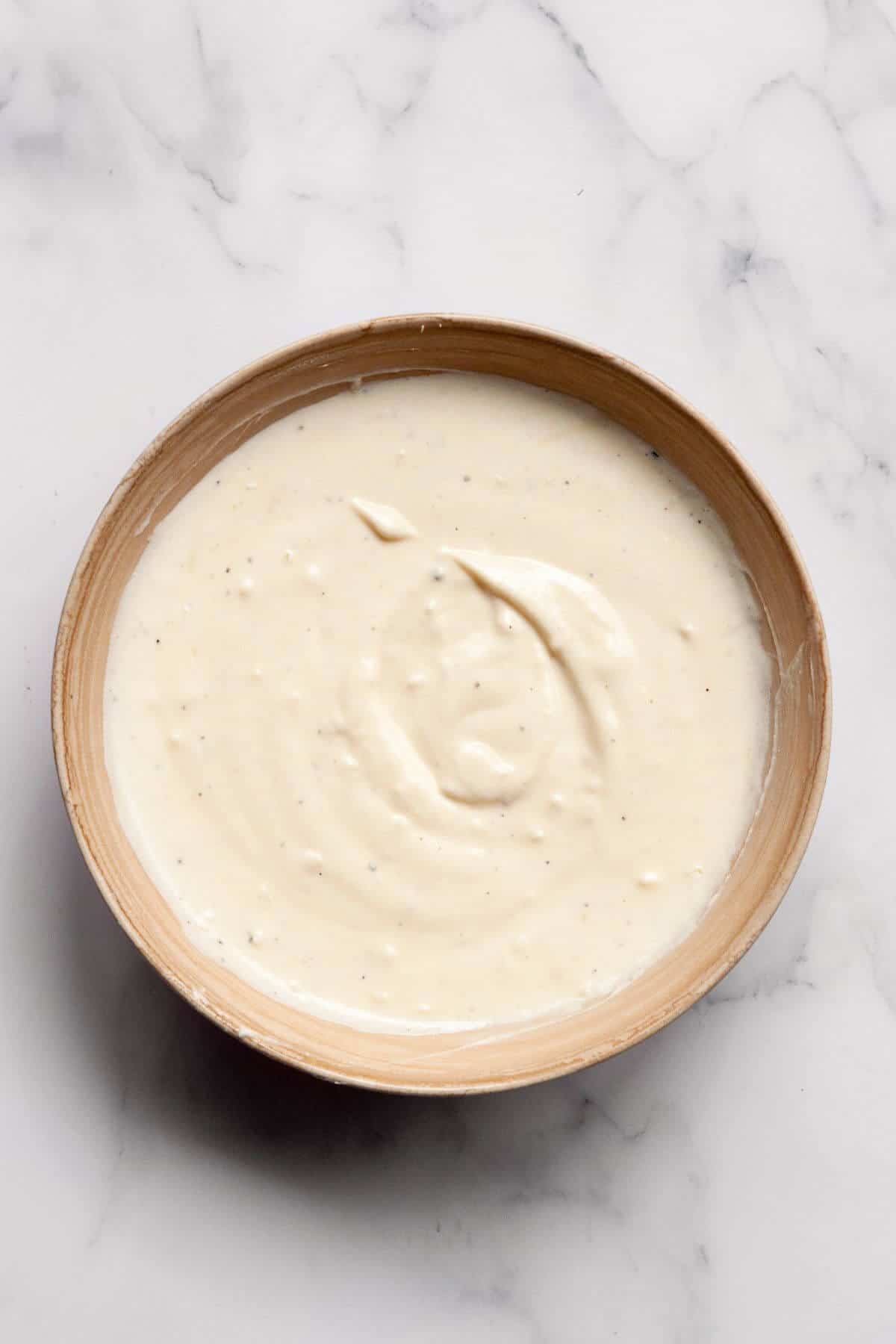 Greek yogurt Caesar salad dressing in a mixing bowl before mixing — creamy, tangy, and made without mayo or anchovies.