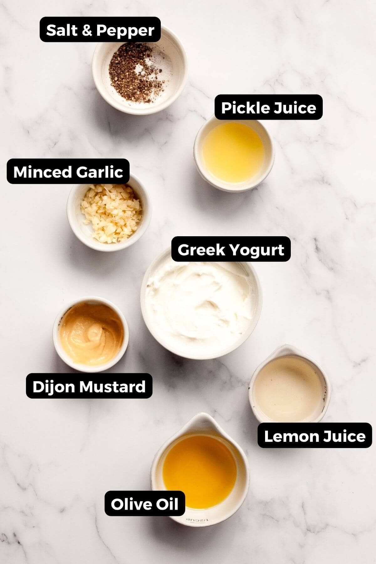 All ingredients in healthy Caesar salad dressing including Greek yogurt, garlic, Dijon mustard, pickle juice, salt & pepper, and lemon juice.