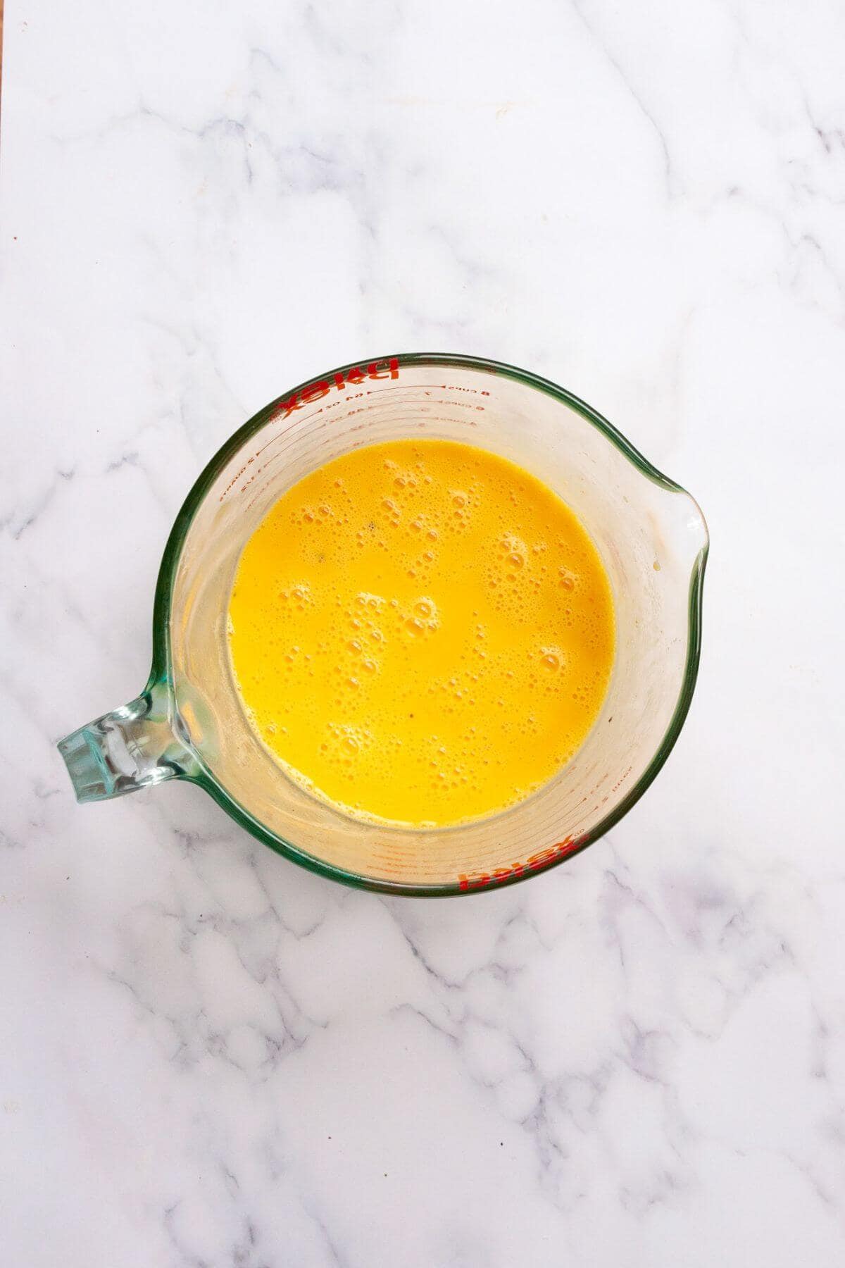 Whisked egg mixture in a glass measuring cup for keto egg bites.