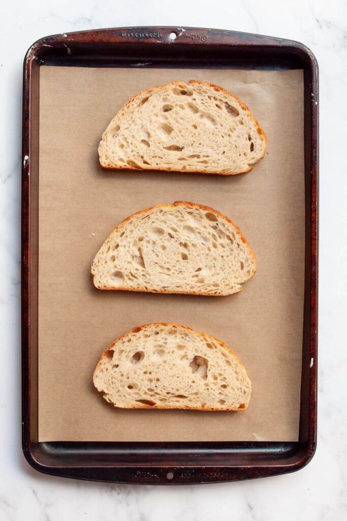 three slices of sourdough bread on a baking sheet