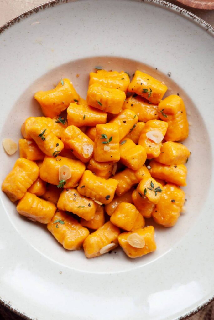 sweet potato gnocchi in a bowl with garlic and thyme