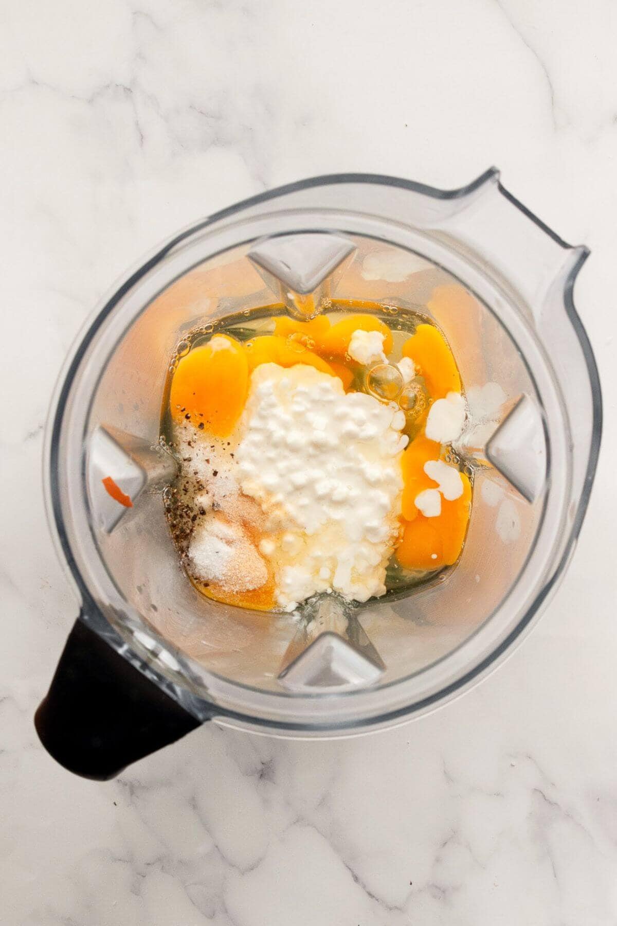 Eggs, cottage cheese, and seasonings added to a blender before blending.