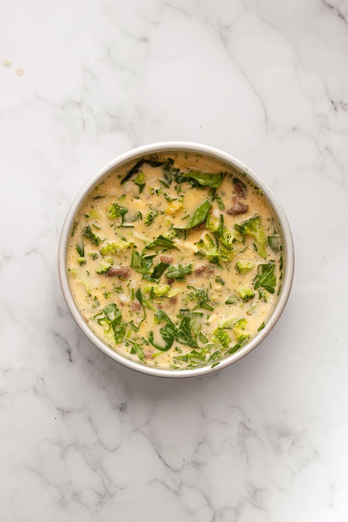 Blended egg mixture poured over the vegetable and sausage filling in the pan.
