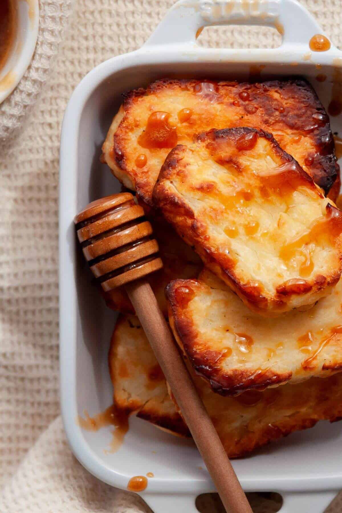 Golden crispy air fryer halloumi in a serving dish with honey drizzled on top.