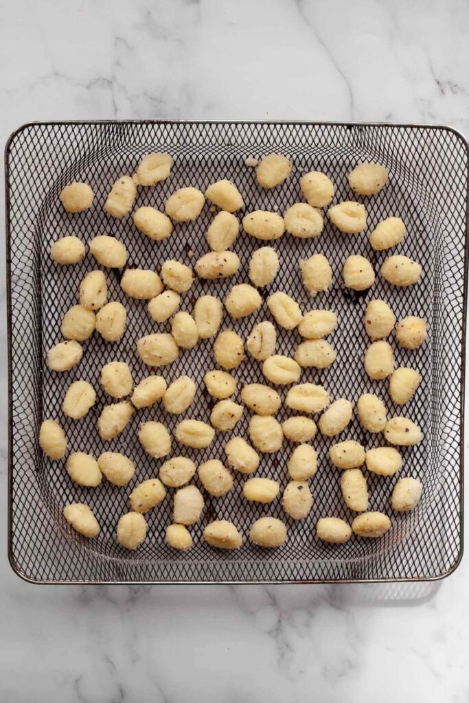 raw, seasoned gnocchi in air fryer basket before being cooked