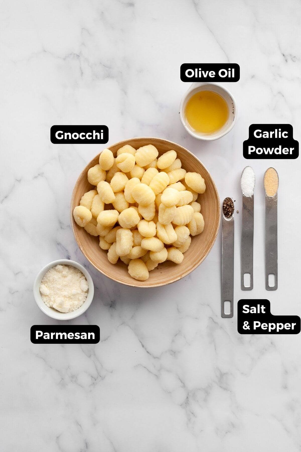 The five ingredients in this recipe in small bowls with labels, including: gnocchi, olive oil, garlic powder, parmesan, salt, and pepper.
