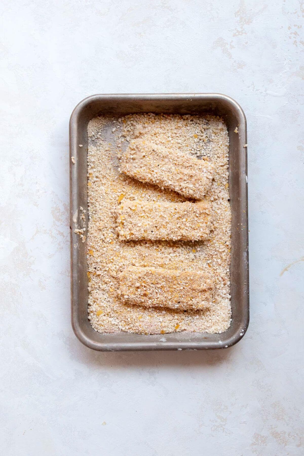 Breaded tofu schnitzel coated in seasoned panko and nutritional yeast on a sheet pan.