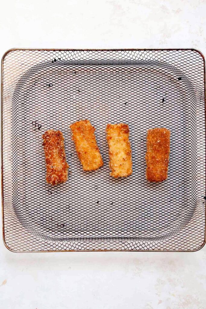 four pieces of crispy tofu schnitzel in air fryer basket after being air fried