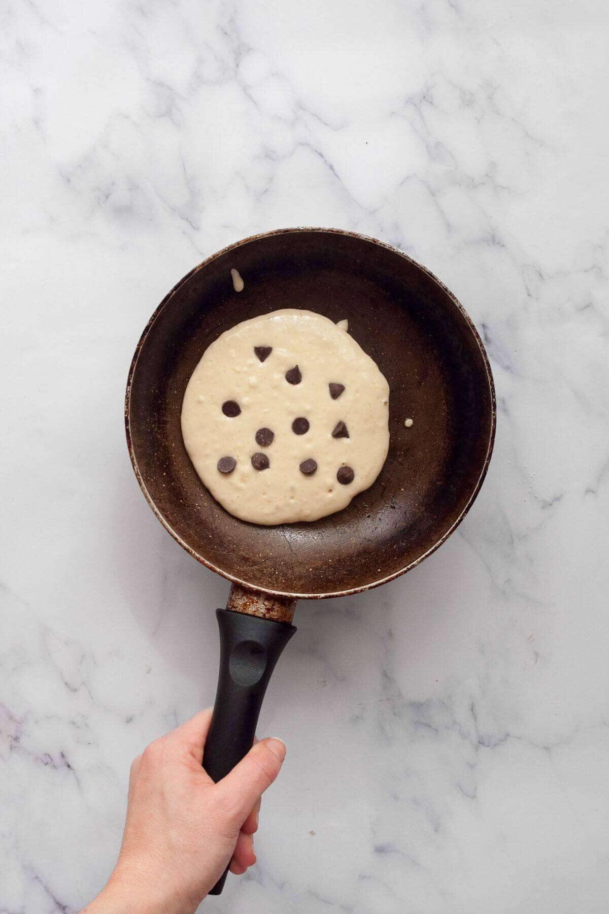 Oat milk pancake batter in greased pan with chocolate chips.