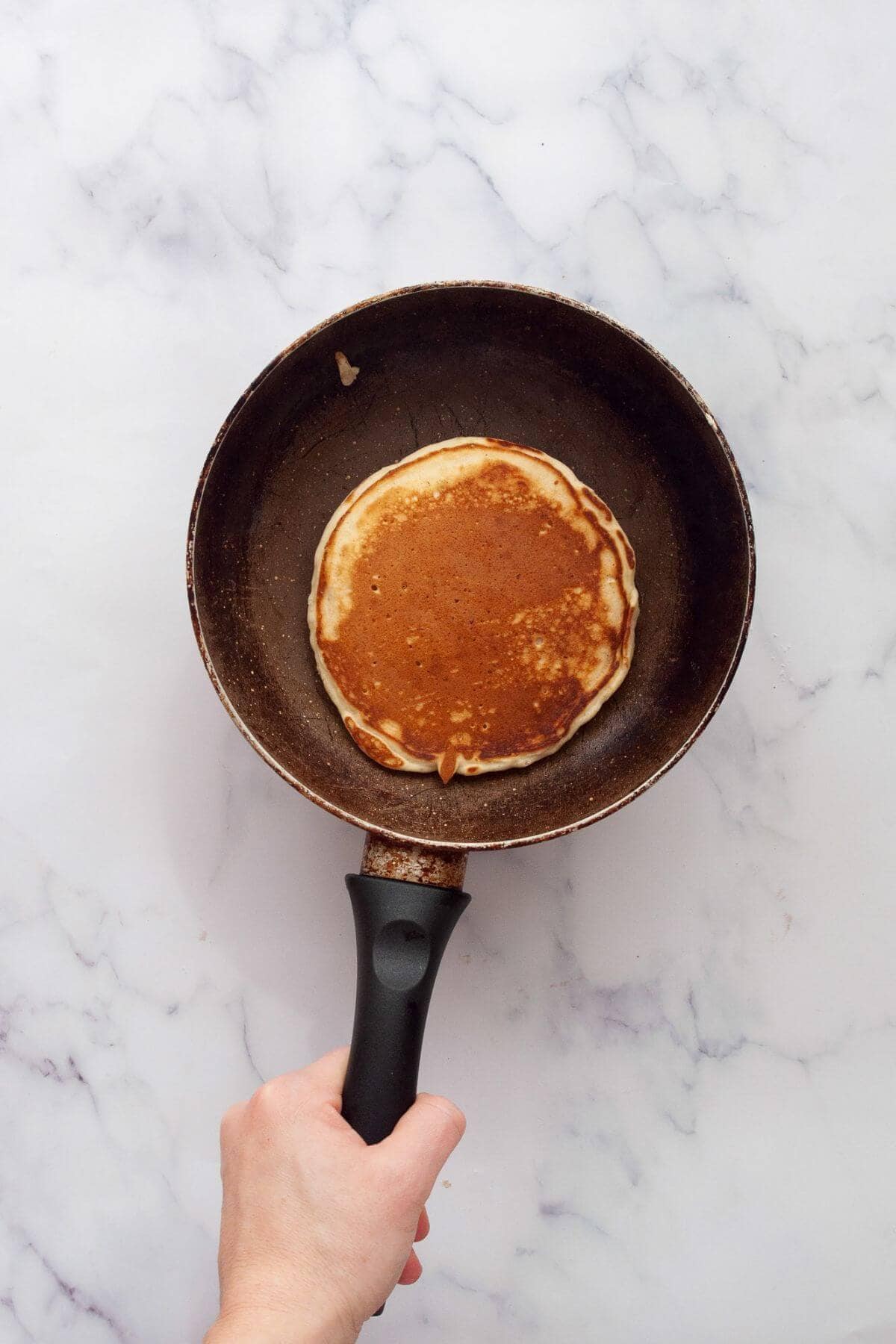 Cooking an oat milk pancake in a pan.
