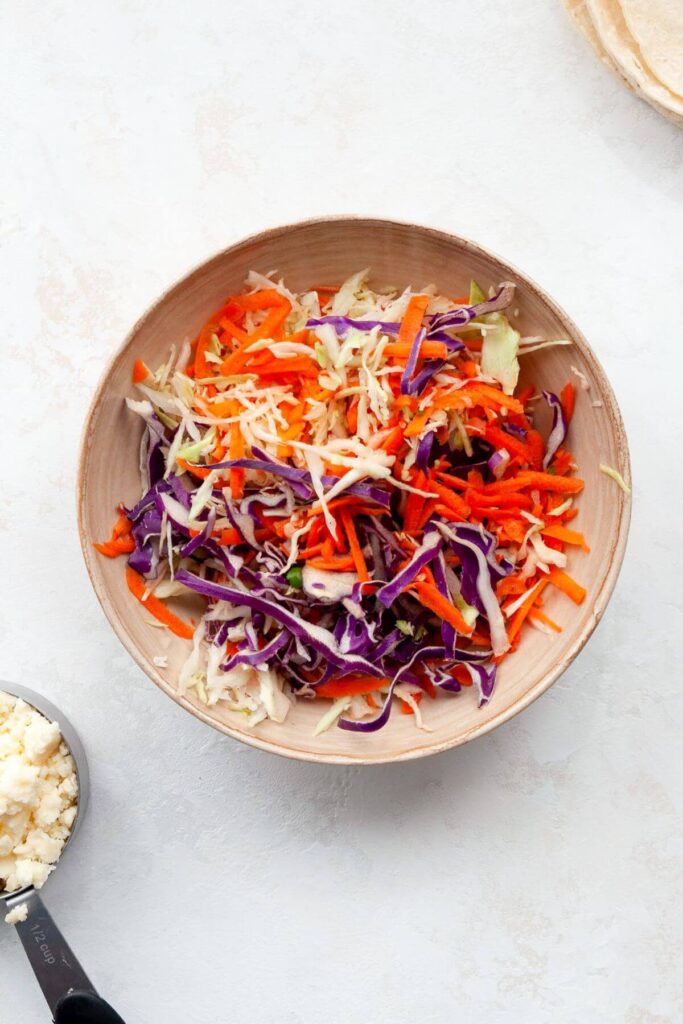 healthy carrot cabbage slaw in a mixing bowl