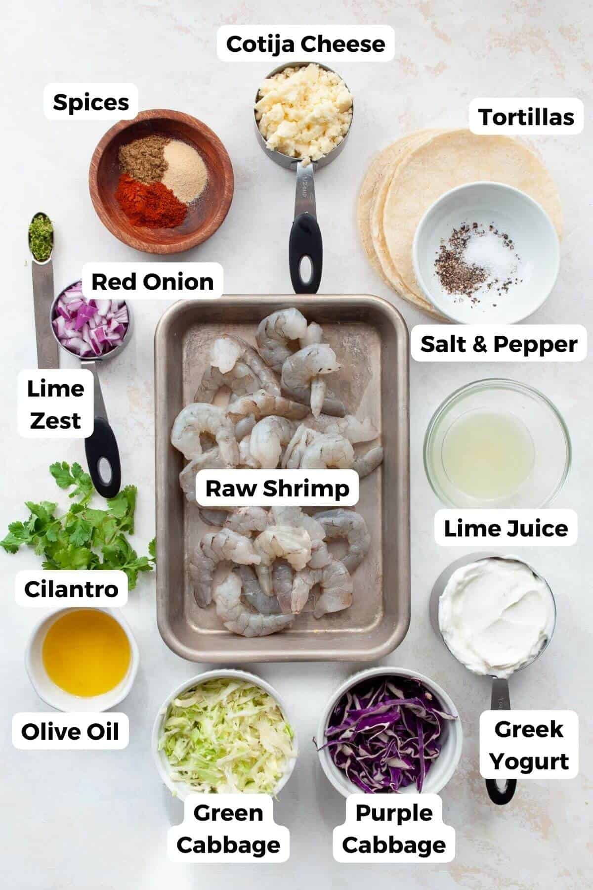 all ingredients in baja shrimp tacos in bowls including shrimp, greek yogurt, cilantro, cabbage, lime, spices, salt, pepper, tortillas, and red onion