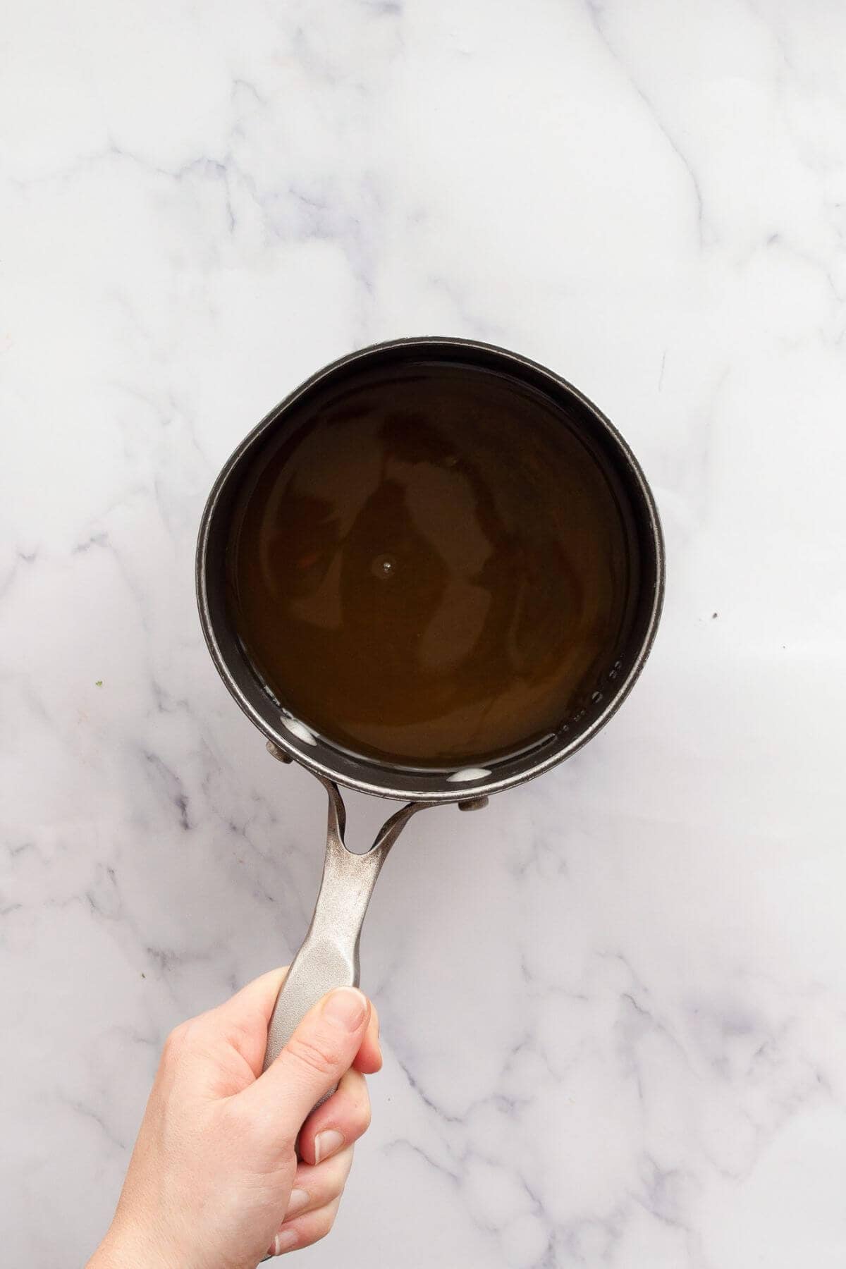 Dissolving honey in warm water in a saucepan to make lemonade popsicles.