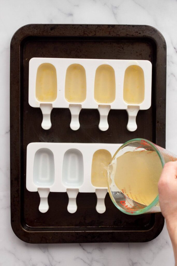 pouring homemade lemonade into popsicle molds