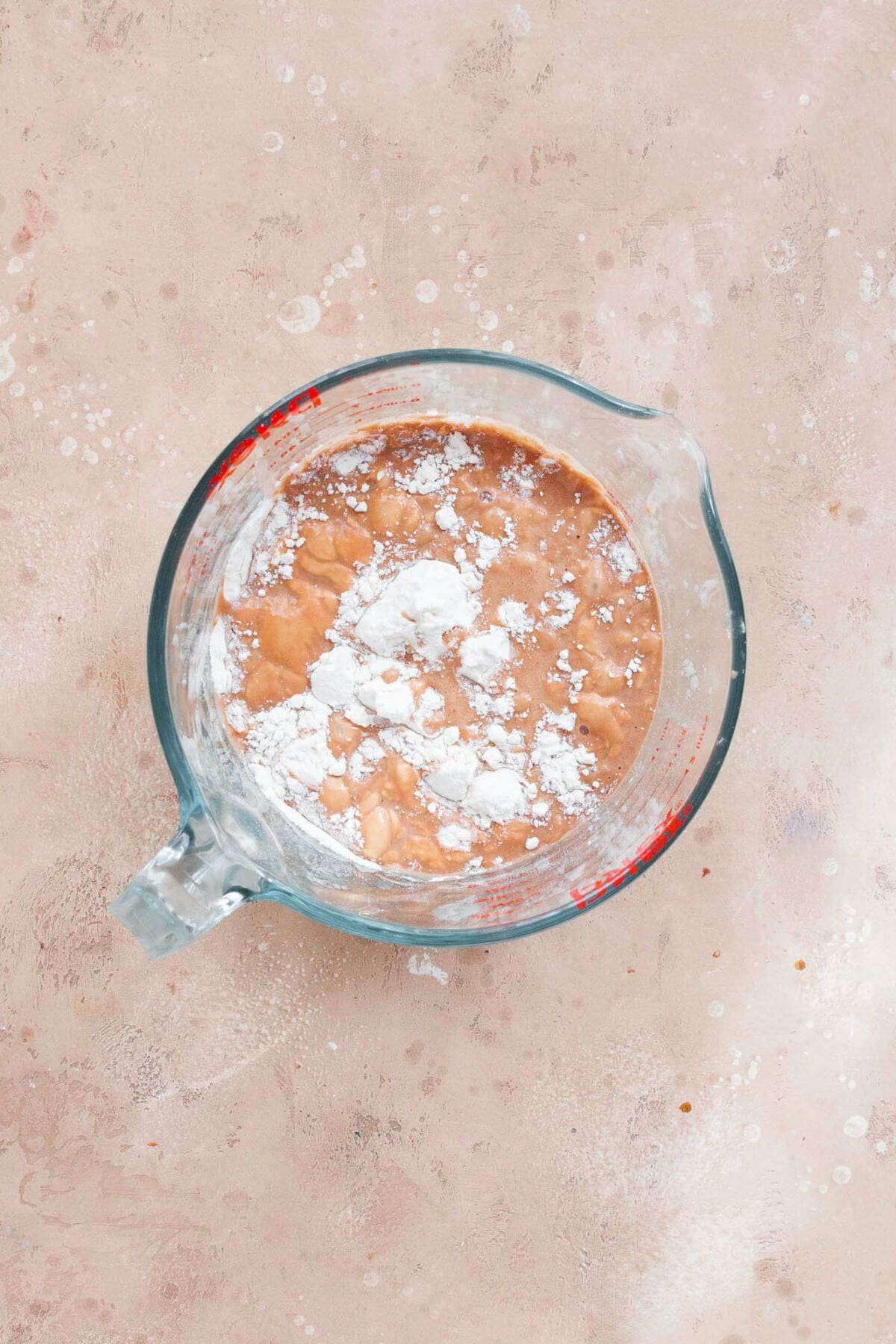 Flour and dry ingredients added to Nutella milk in a glass measuring cup.