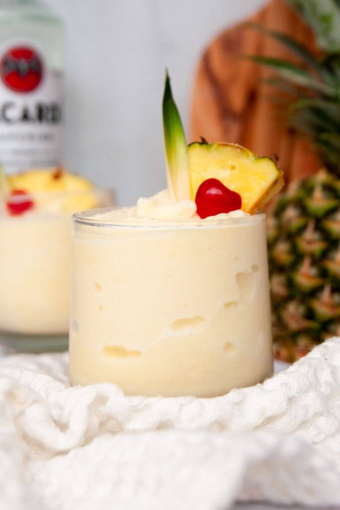 Bacardi pina colada in a glass with fresh pineapple and a cherry