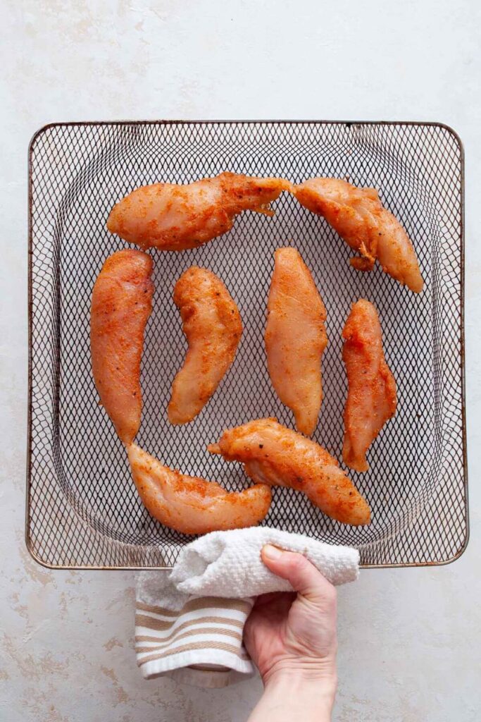 uncooked chicken tenders without breading in an air fryer basket