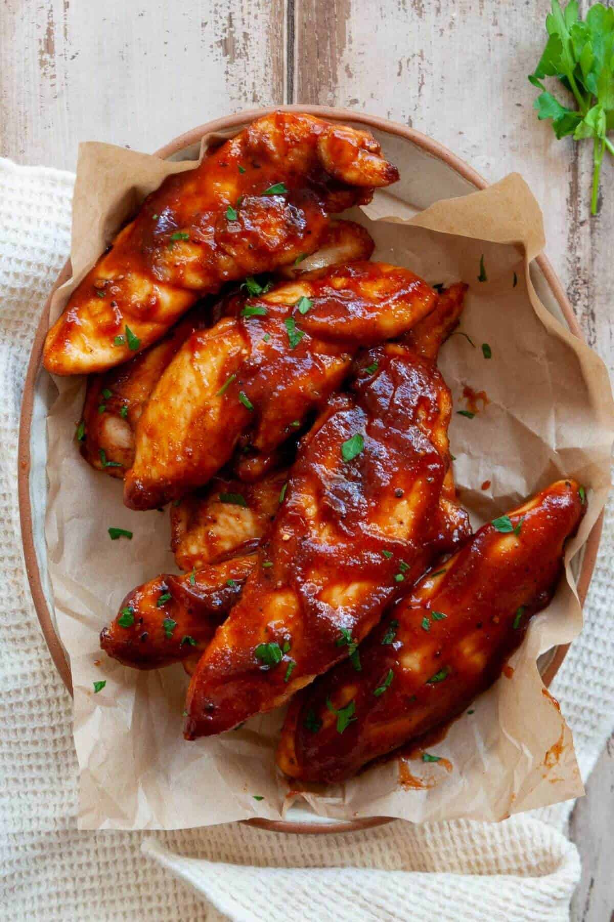 Keto air fryer chicken tenders without breadcrumbs and coated in sauce.