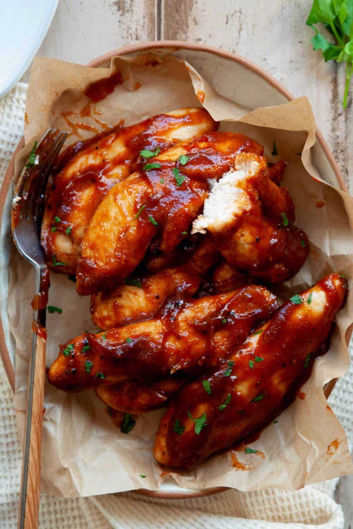Bite shot of juicy BBQ chicken tenders made in the air fryer with no breading.