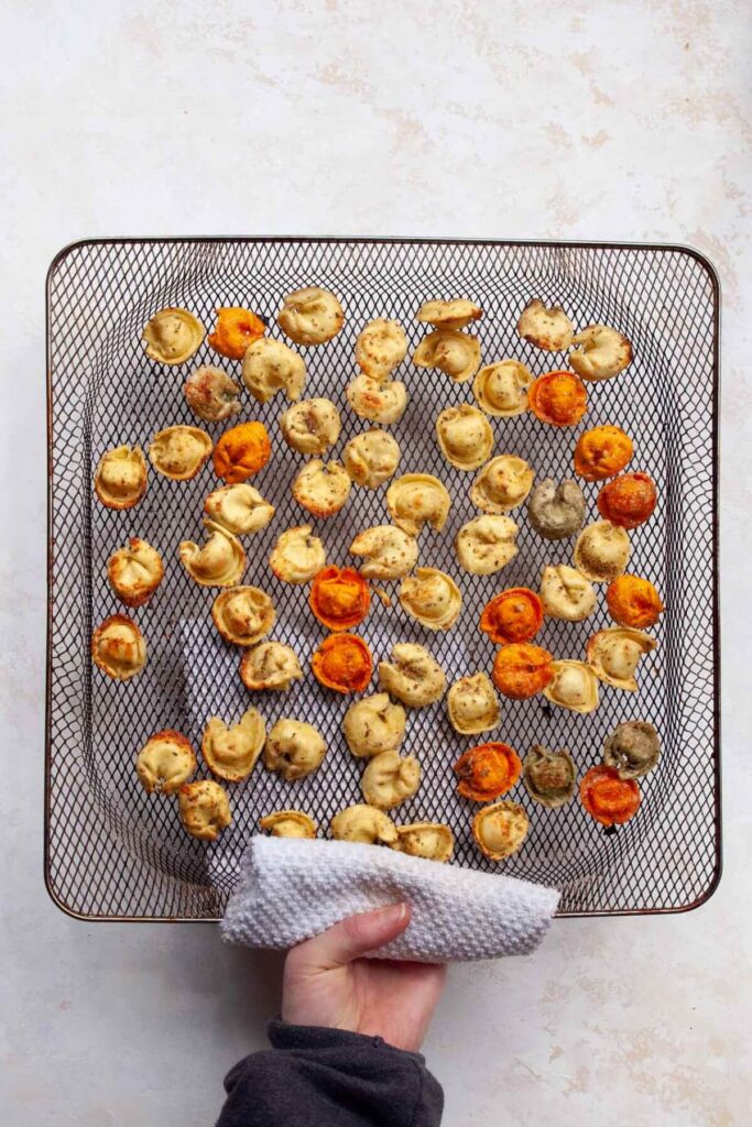 crispy tortellini in an air fryer basket after air frying
