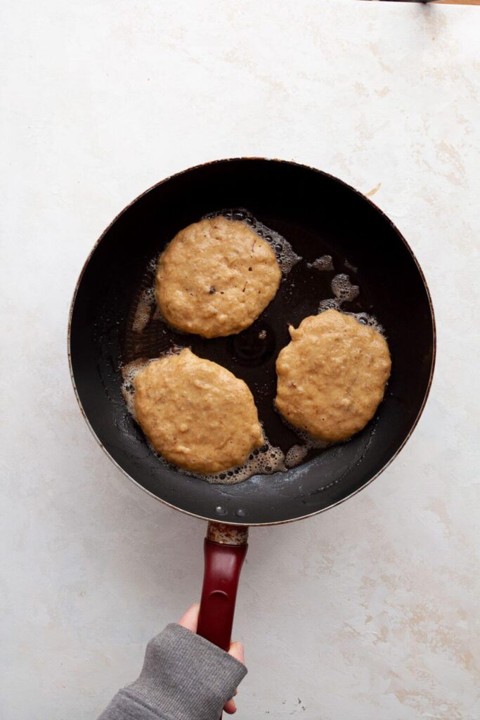 cooking 3 almond flour pancakes in a buttered saute pan