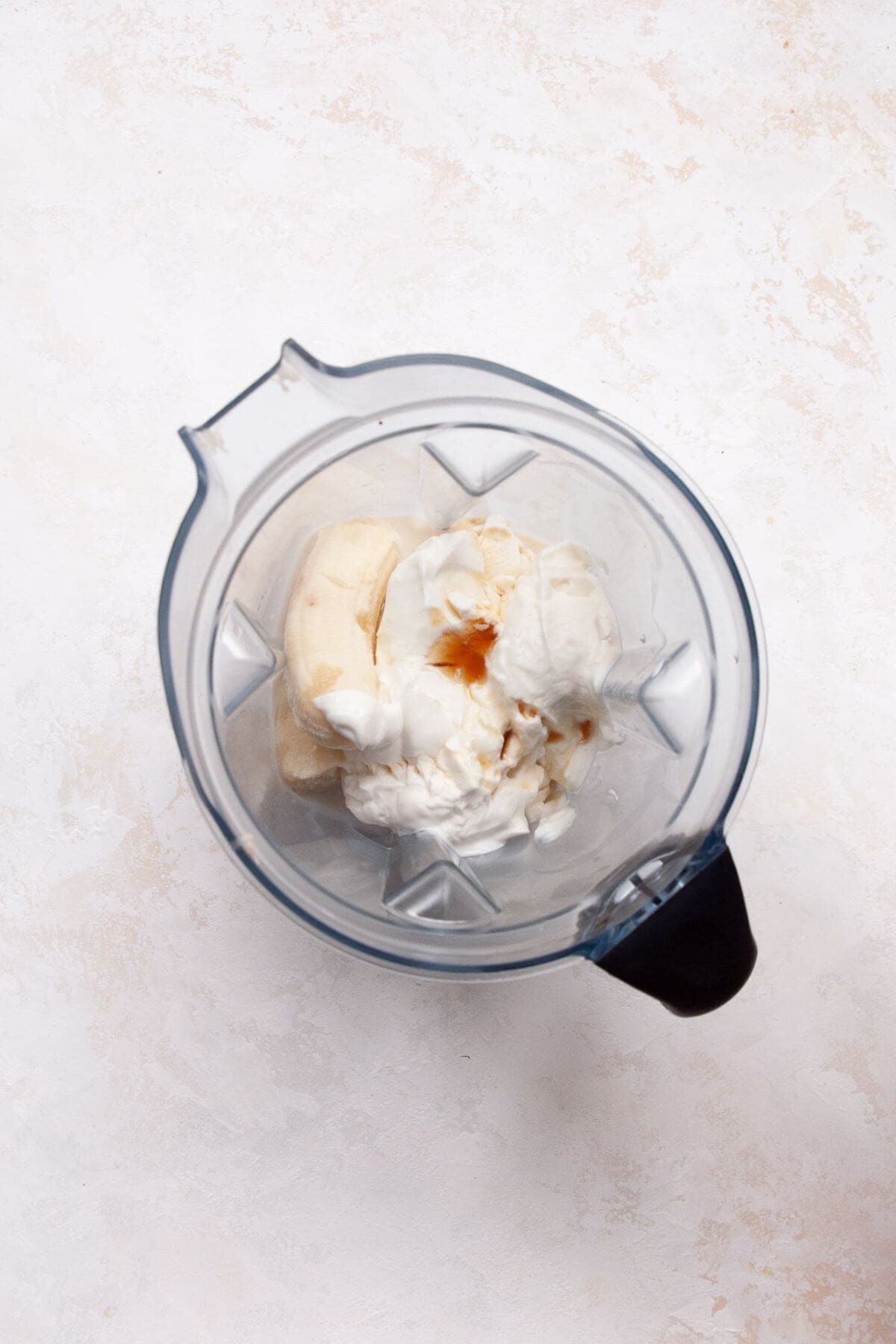 All the banana popsicle ingredients-bananas, yogurt, vanilla, maple syrup, milk, and cinnamon-added to a blender before blending.