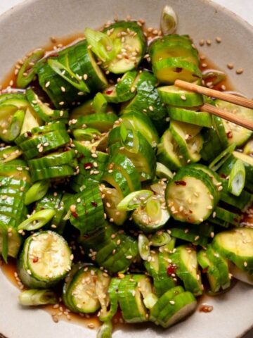 Spicy Asian cucumber salad with accordion-cut cucumbers in a garlicky soy-chili dressing topped with green onion and sesame seeds.